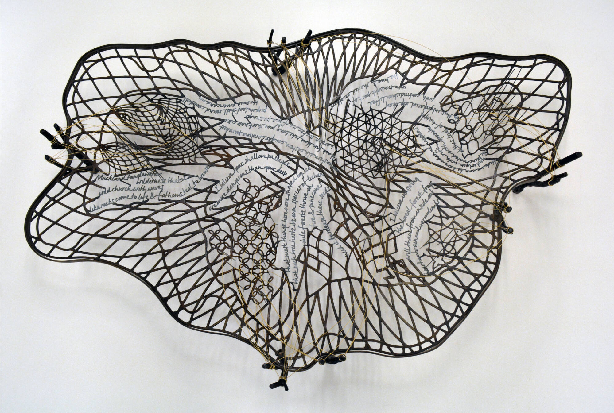 Steel sculpture of small pieces woven together to create a topographical map texture with words.